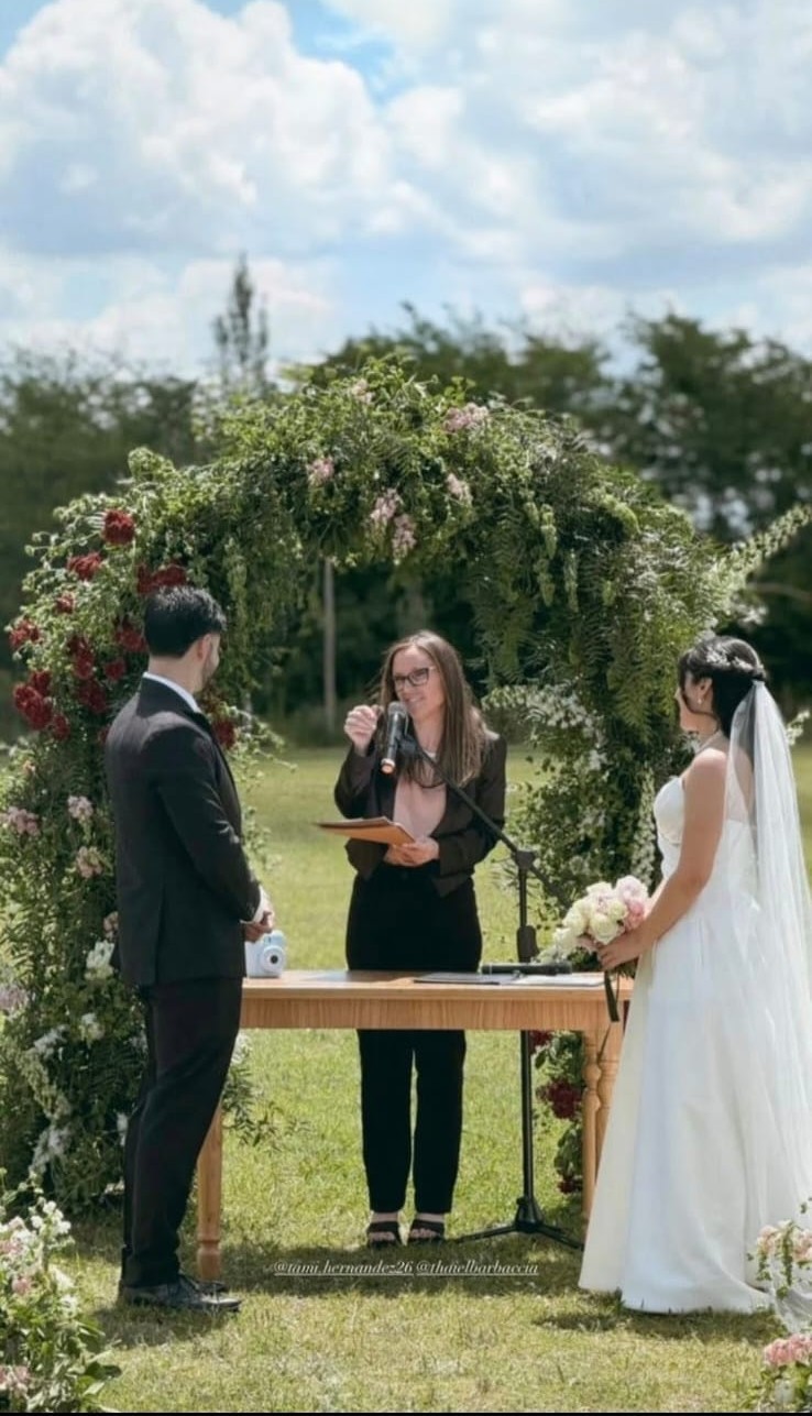 Ceremonia de boda al aire libre, bajo un arco de flores rojas y blancas